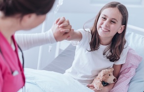 Little girl holding hands with someone sitting in bed
